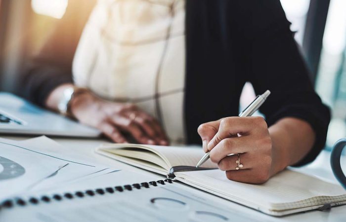 Cropped shot of a businesswoman making notes at her desk in a modern office
